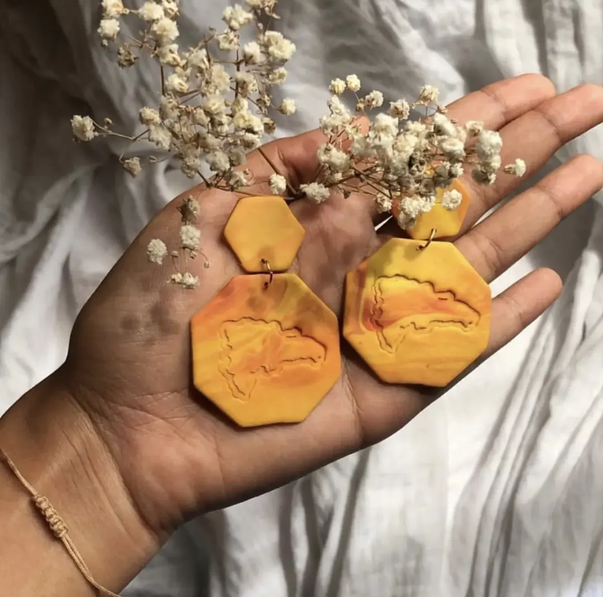 Aretes Atardecer: hexágonos naranja y amarillo en la mano